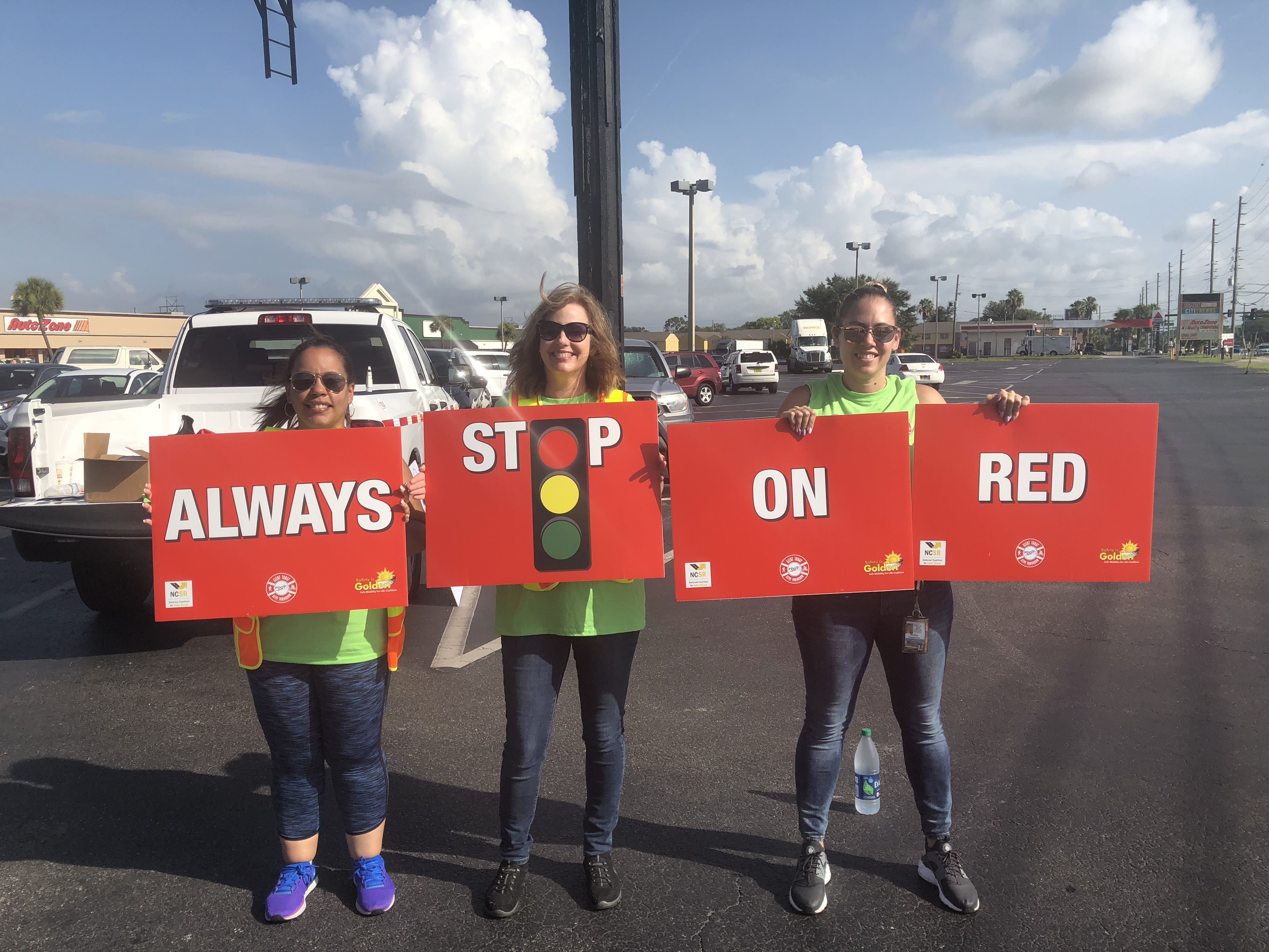 Personas soteniendo carteles que dicen 'deténgase siempre en semáforo en rojo'