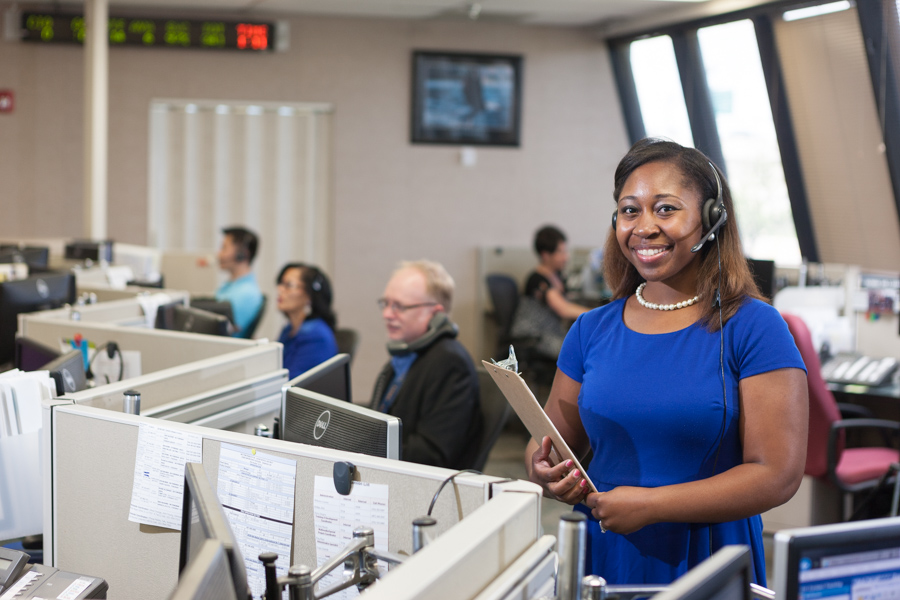 Una mujer en un centro de llamadas al 311 sonríe mientras otros trabajan en sus escritorios