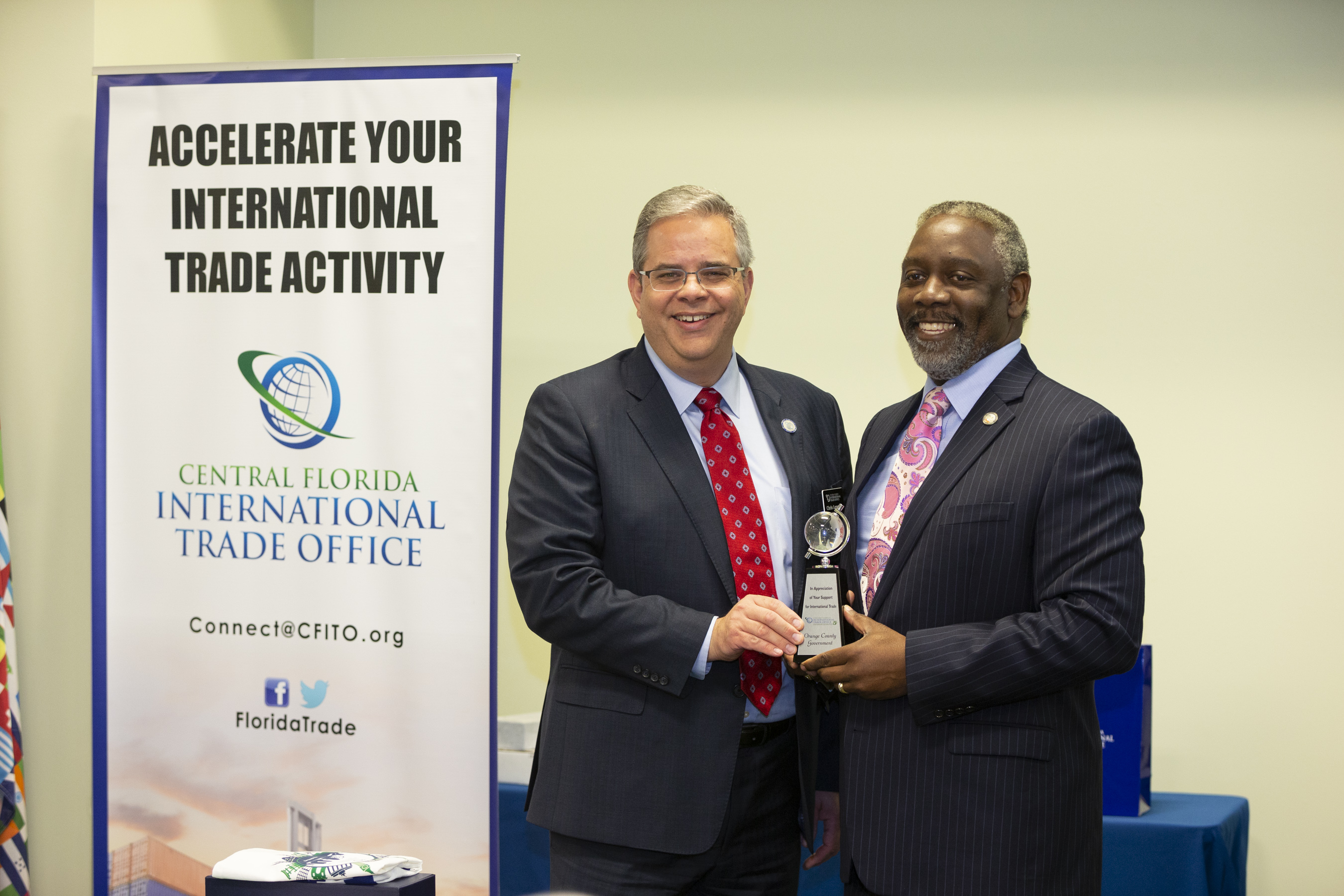 Central Florida International Trade Office Program Manager Christopher Leggett stands with Orange County Mayor Jerry L. Demings as they both hold an award.