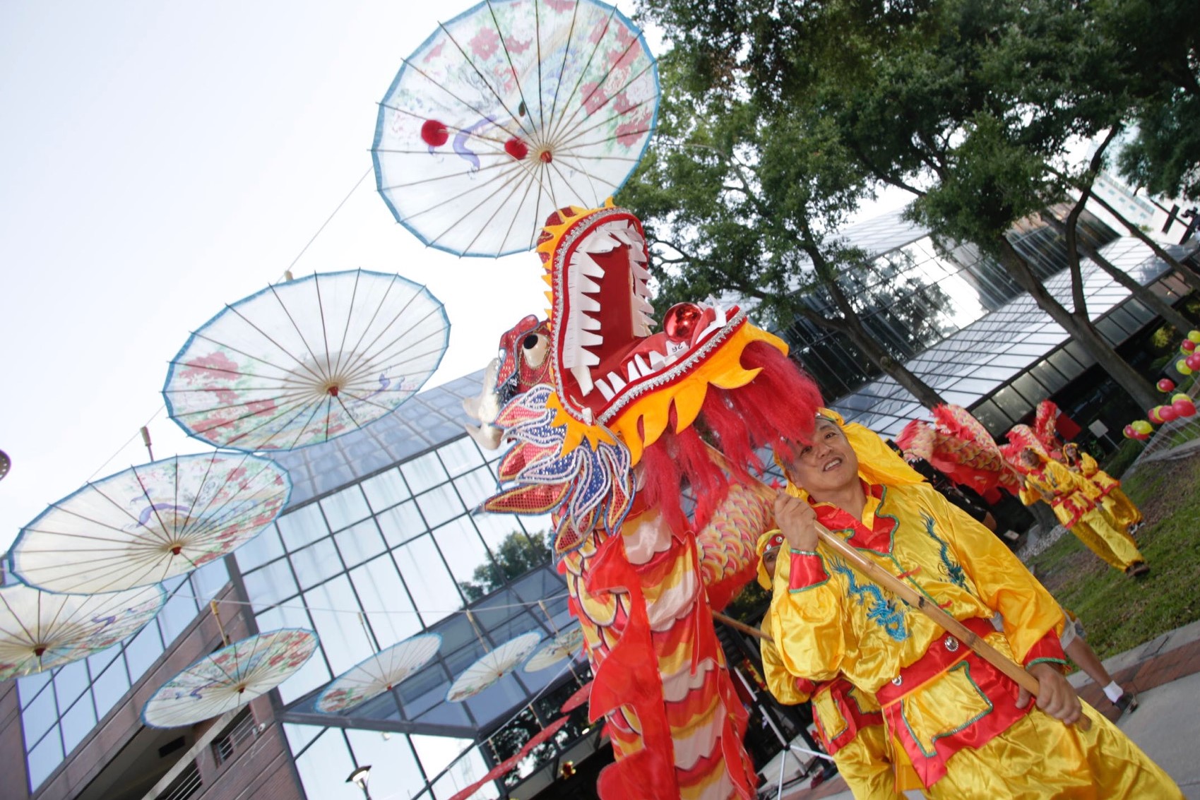 Un hombre con un tradicional atuendo rojo y amarillo realiza una danza con un dragón decorativo