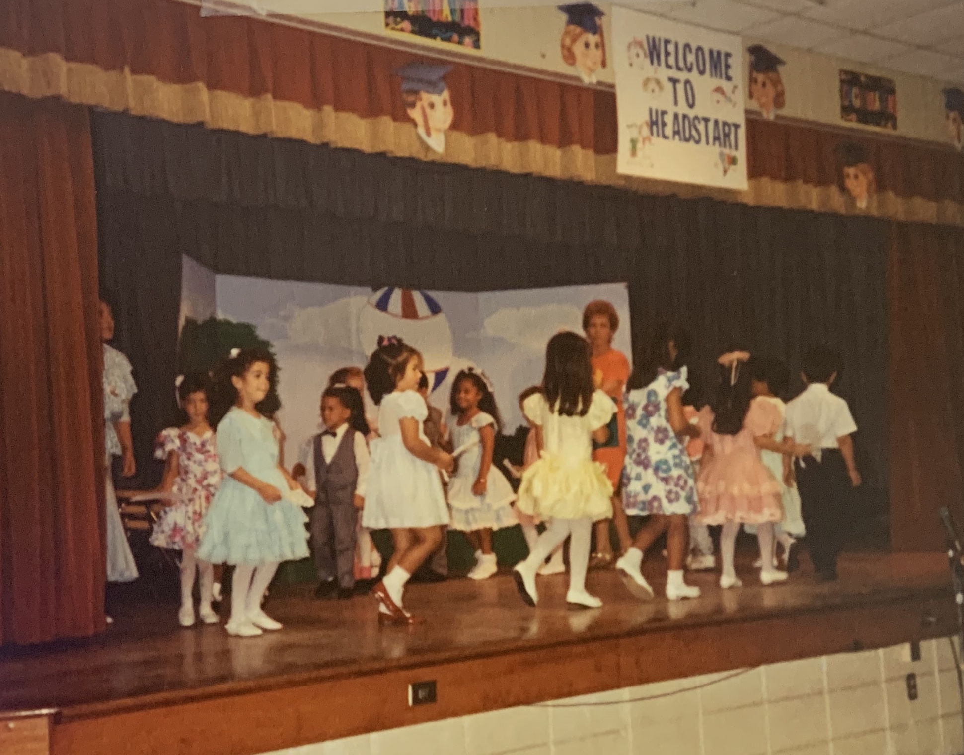 Schoolchildren performing onstage. The words "Welcome to Head Start" are above them.