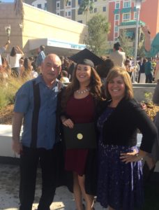 Yesenia y sus padres posan para una foto de graduación