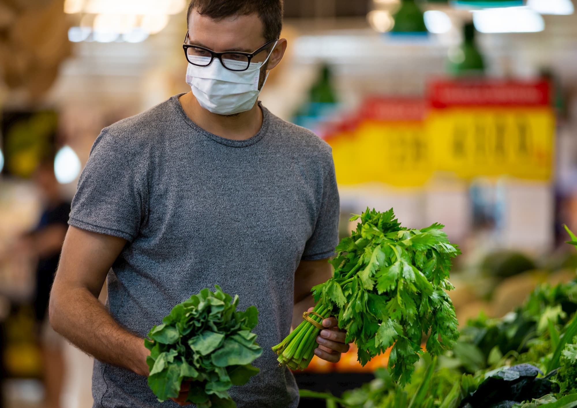 Man grocery shopping while wearing a mask