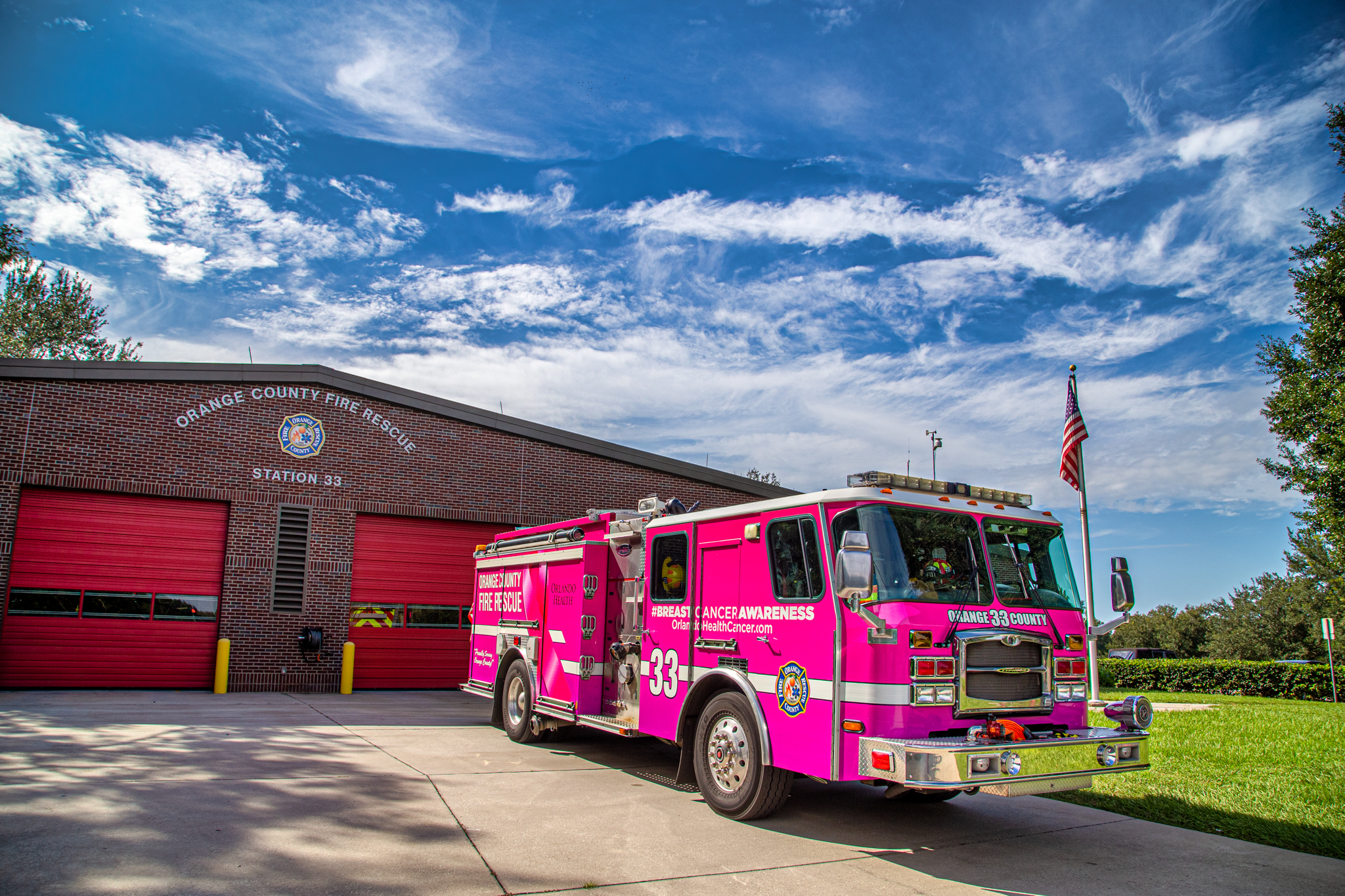 Un camión de bomberos rosado en la estación de bomberos