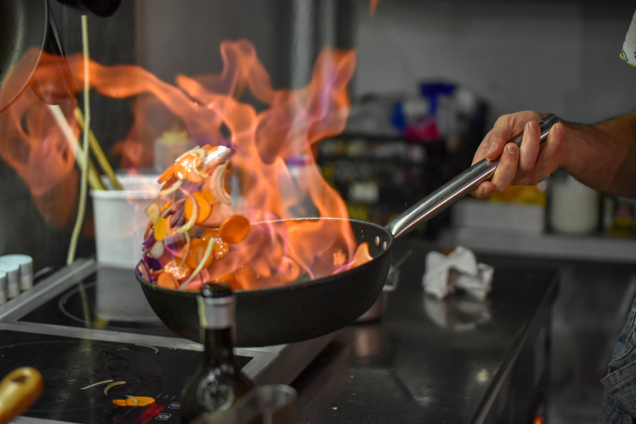 A person cooking on a skillet that has gone up in flames