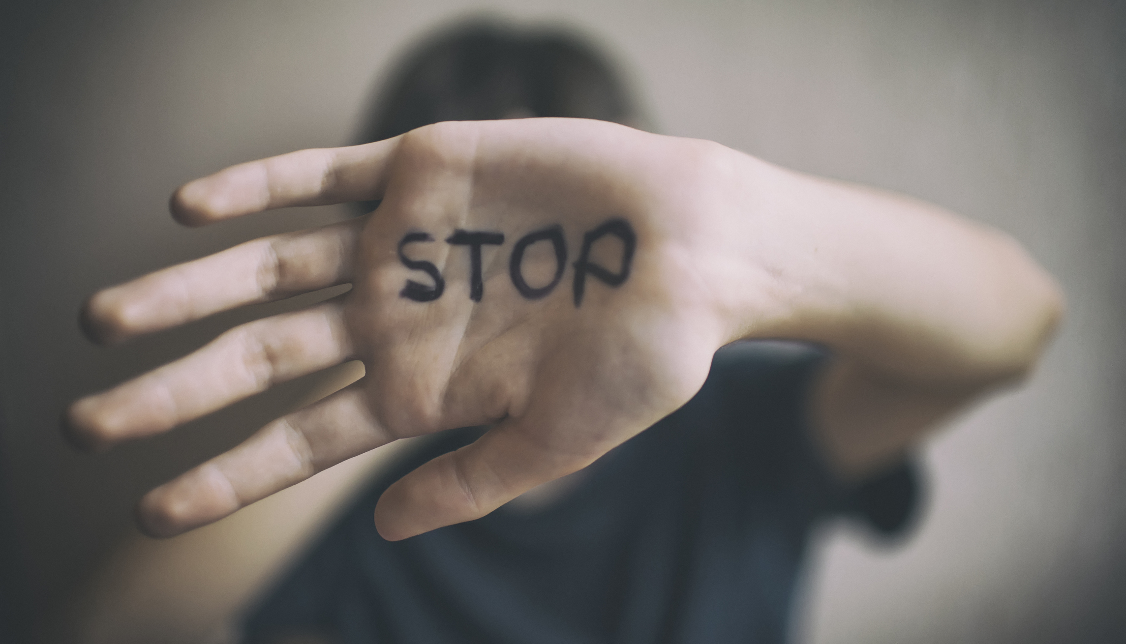 A man protects himself with his hand with. The word Stop is written on his hand.