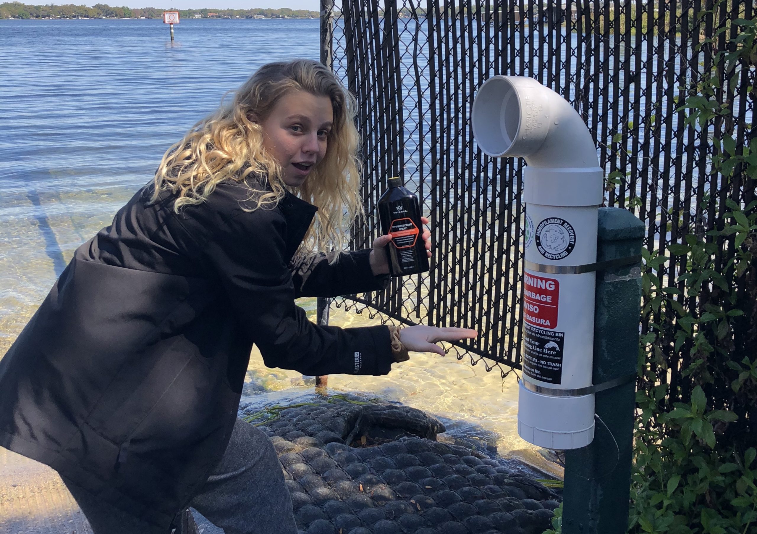 Una mujer en una rampa para botes señalando un contenedor de desechos