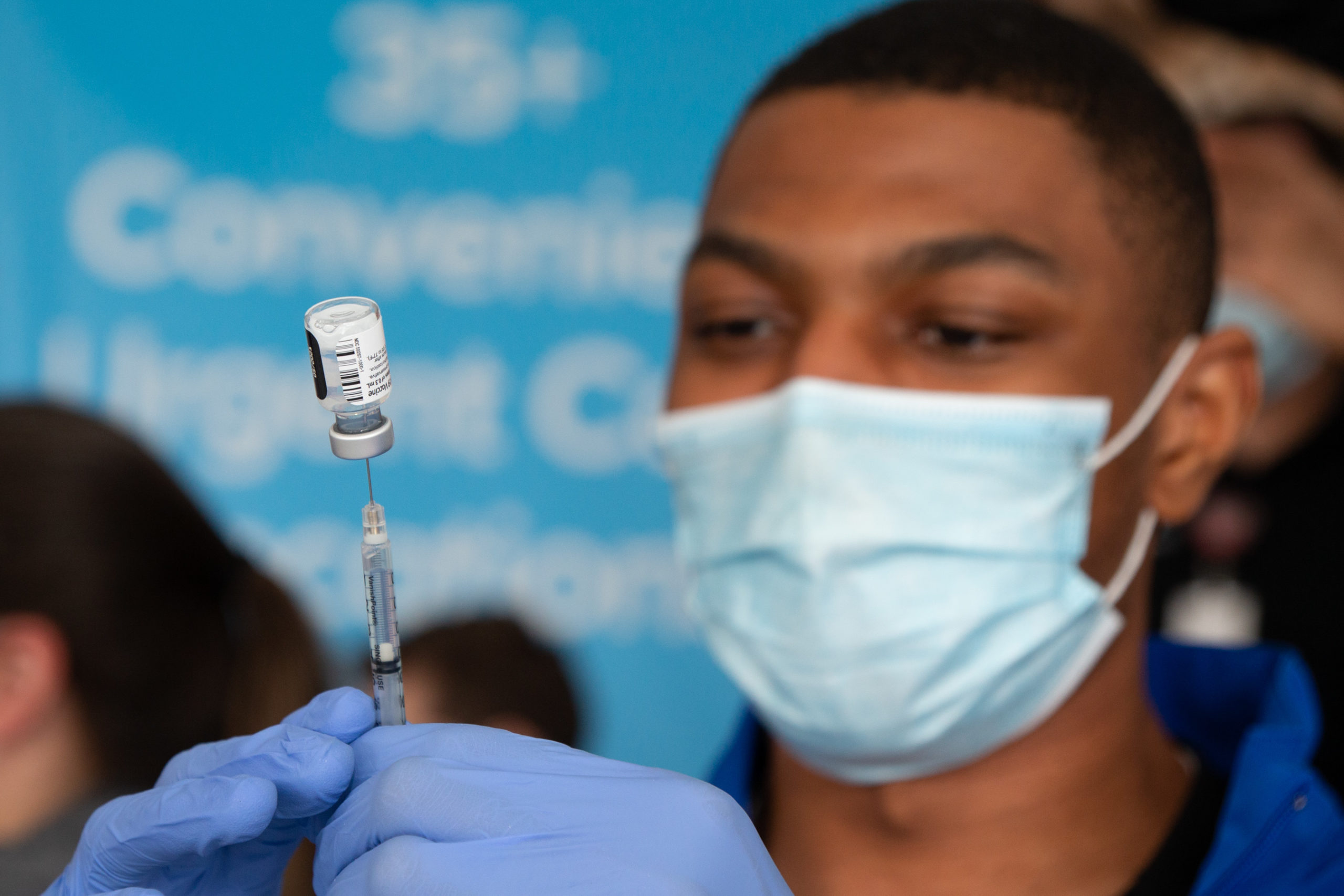 male nurse filling a syringe with COVID-19 vaccine.