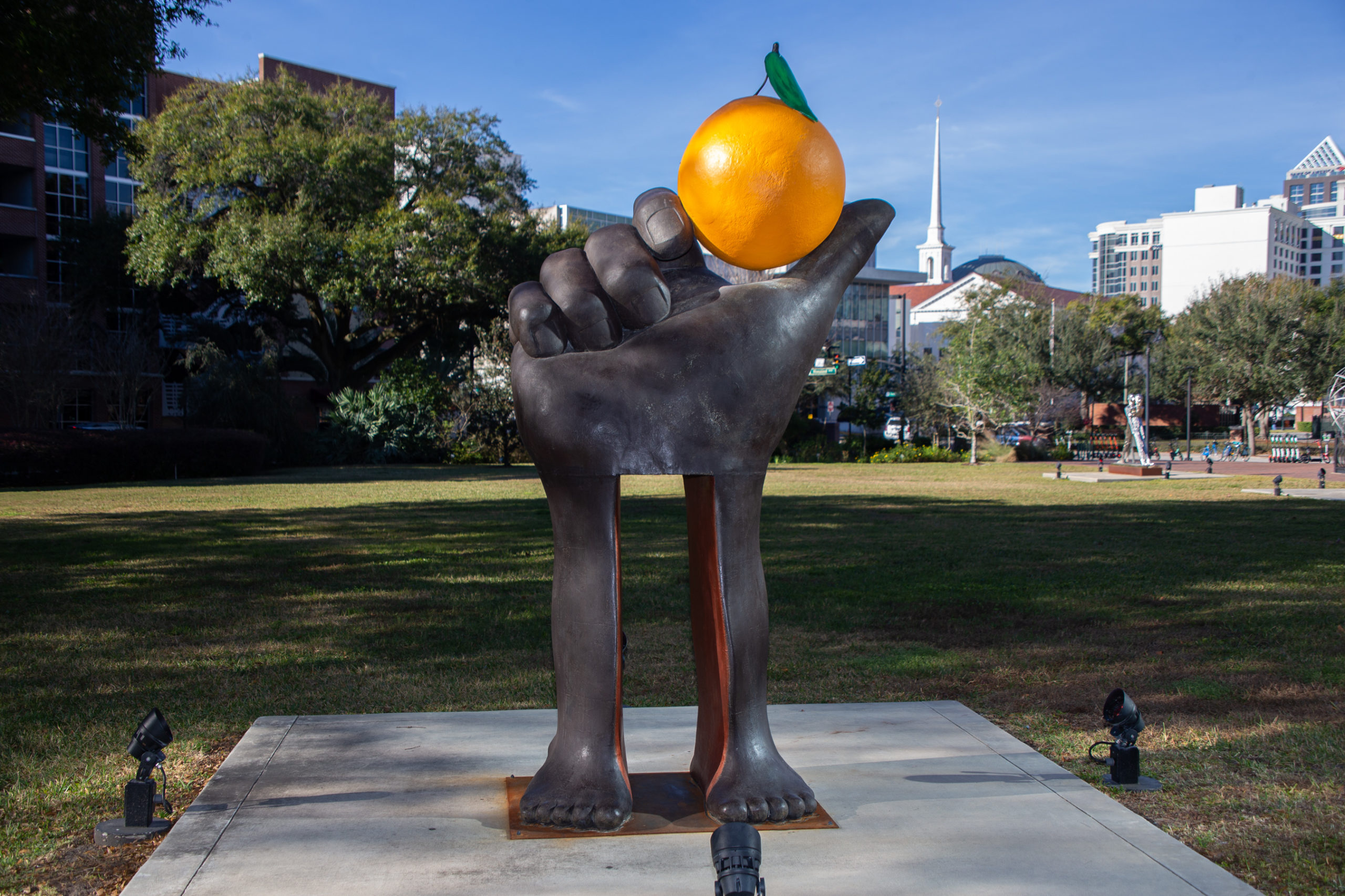 escultura de una mano sosteniendo una naranja