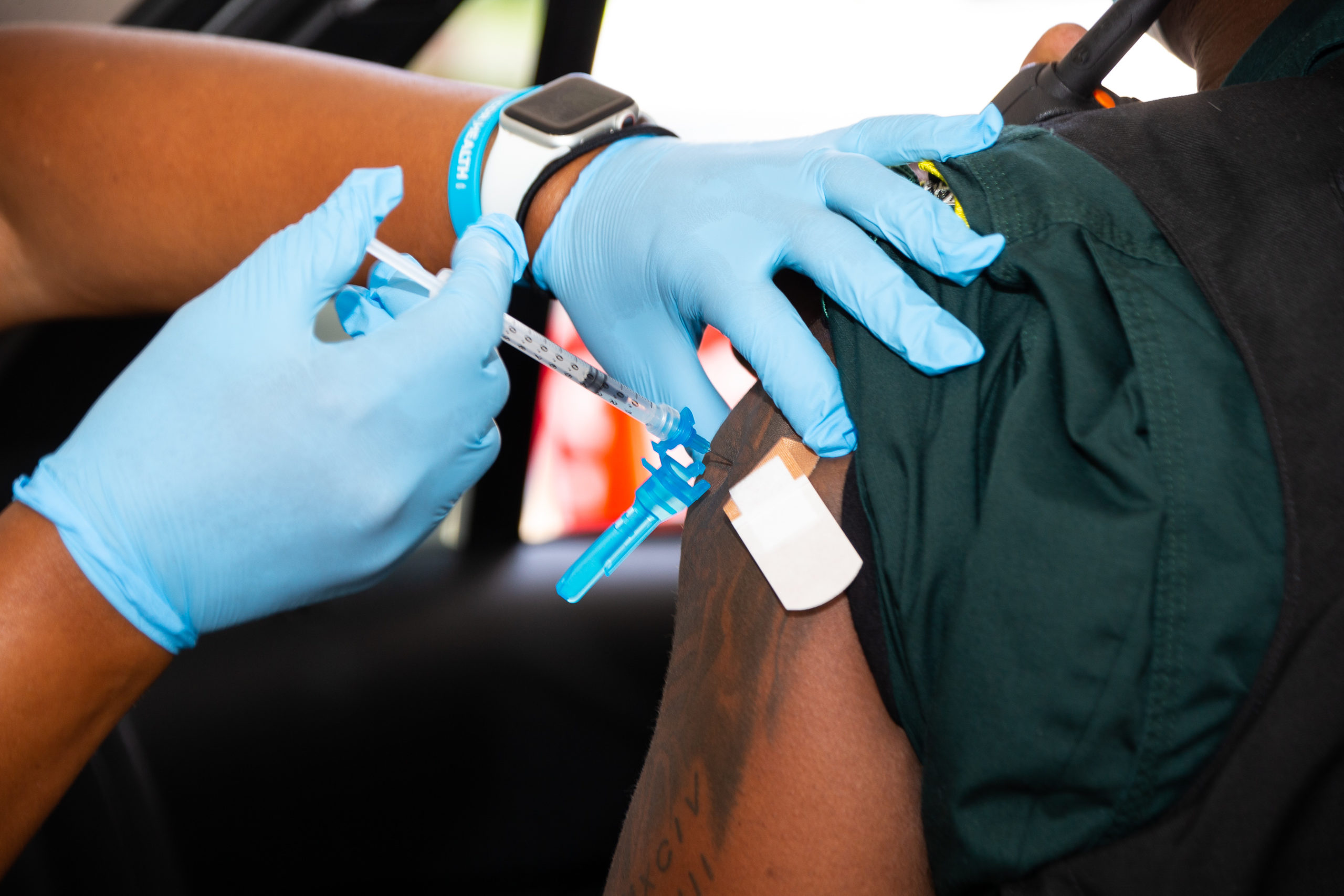 hands on arm administering a COVID-19 vaccine